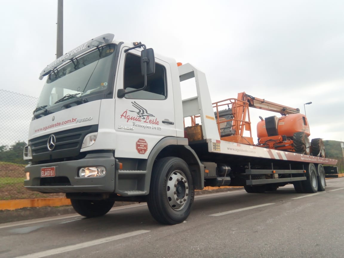 Caminhão prancha Águia Leste transportando plataforma elevatória em rodovia de São Paulo